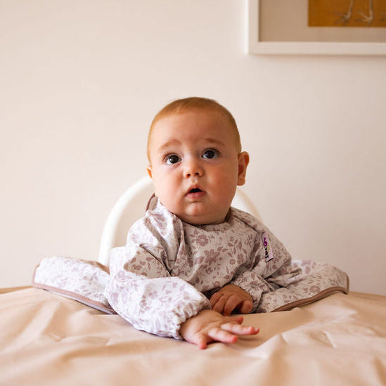Baby sitting in a high chair with a neutral background